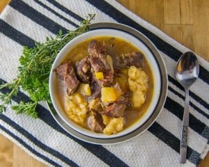 St. Kitts and Nevis Goat Water Stew in a white bowl with parsley and thyme garnish