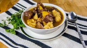 St. Kitts and Nevis Goat Water Stew in a white bowl with parsley and thyme garnish